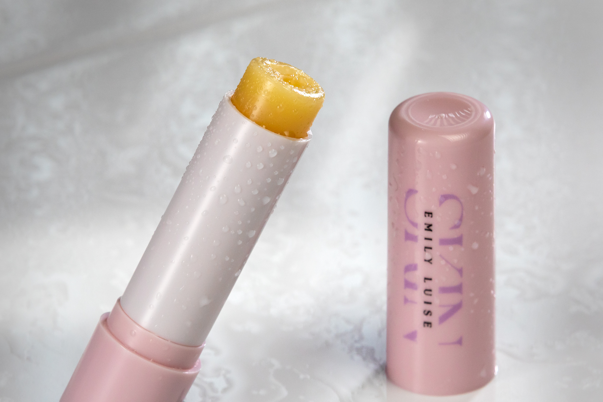 Pink lip balm with cap off on a white background